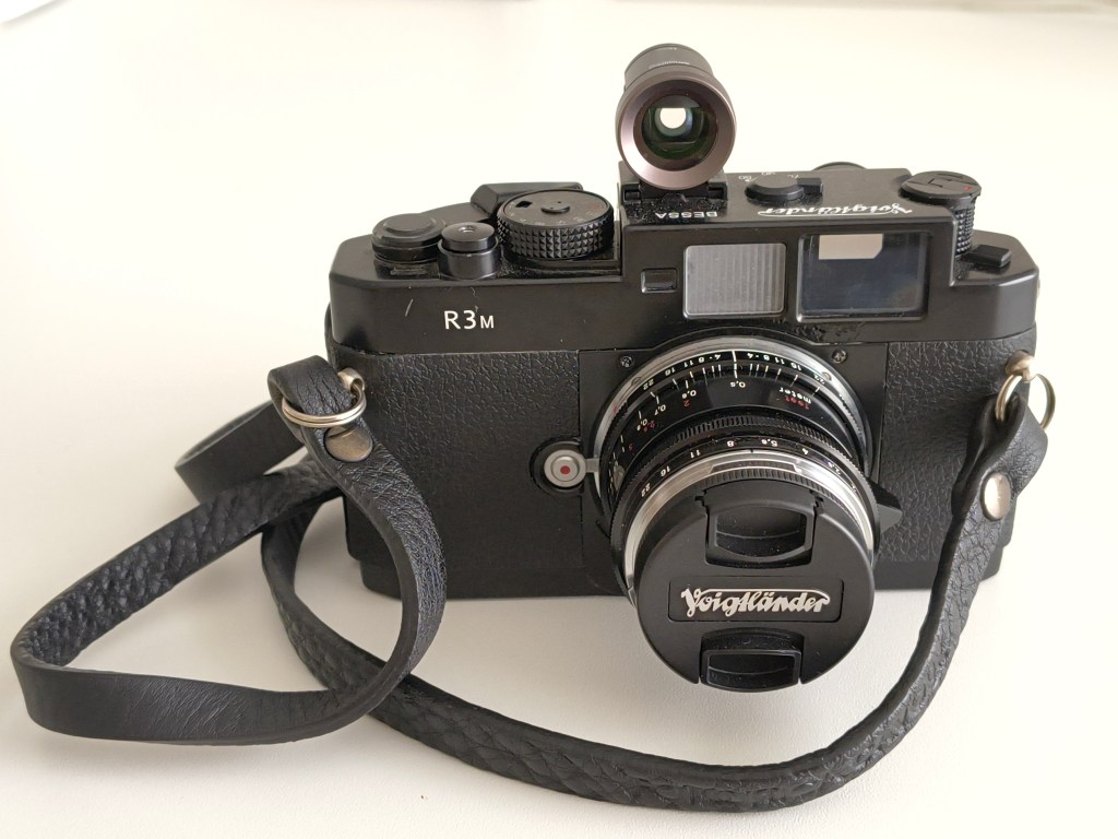 Close-up view of a Voigtländer Bessa R3M camera with a black strap on a light background.