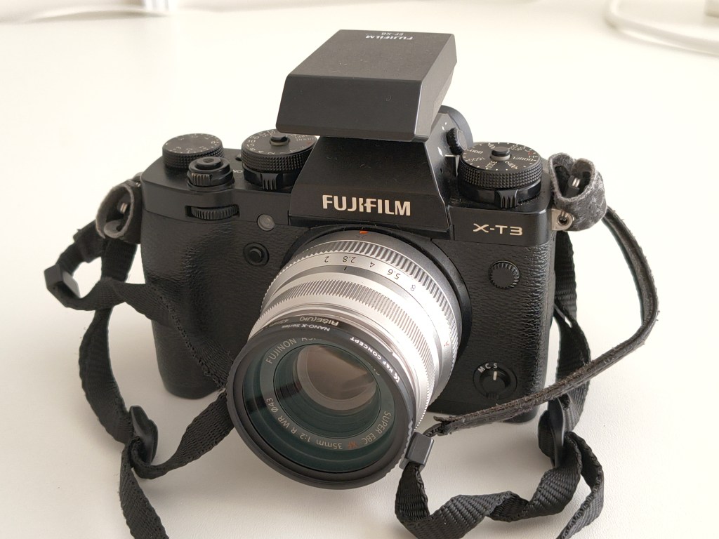 Close-up of a Fujifilm X-T3 camera with a lens, styled in a minimalist setting.